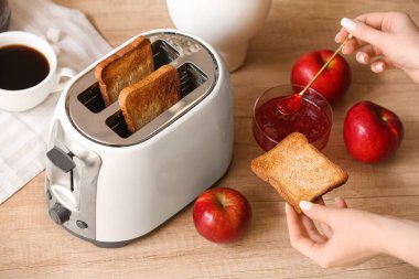 Kızarmış ekmek dilimi ve ahşap masada reçelli kadın.