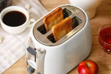 Tahta masada ekmek dilimleri olan beyaz ekmek kızartma makinesi, yakın plan.