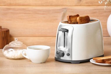 Beyaz ekmek dilimli tost makinesi ve ahşap duvarın yanındaki masada bir fincan kahve.