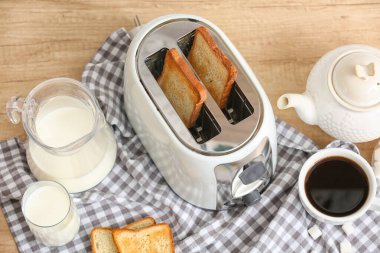 Tahta masada ekmek dilimleri ve içeceklerle beyaz ekmek kızartma makinesi.