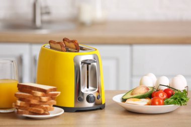Modern mutfaktaki masada sağlıklı yiyecekler bulunan sarı tost makinesi.