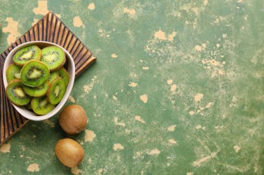 Yeşil arka planda taze kivi dilimleri ile kase