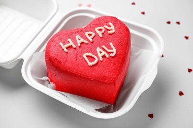 Gri arka planda lezzetli bento keki olan plastik beslenme çantası, yakın plan.