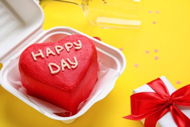 Sarı arka planda lezzetli bento keki olan plastik beslenme çantası, yakın plan.