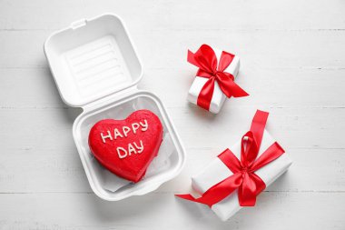 Lezzetli bento kekiyle plastik beslenme çantası ve hafif ahşap arka planda hediyeler.