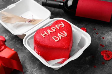 Gri arka planda lezzetli bento keki olan plastik beslenme çantası, yakın plan.