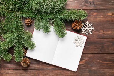 Boş sayfaları ve ahşap arka planda kış dekoru olan açık bir kitap.