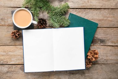 Boş sayfaları, kış dekoru ve ahşap arka planda bir fincan kahvesi olan açık bir kitap.