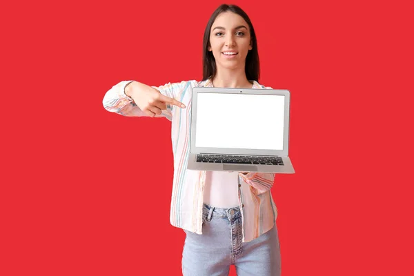 Jonge Vrouw Wijzend Naar Moderne Laptop Rode Achtergrond — Stockfoto