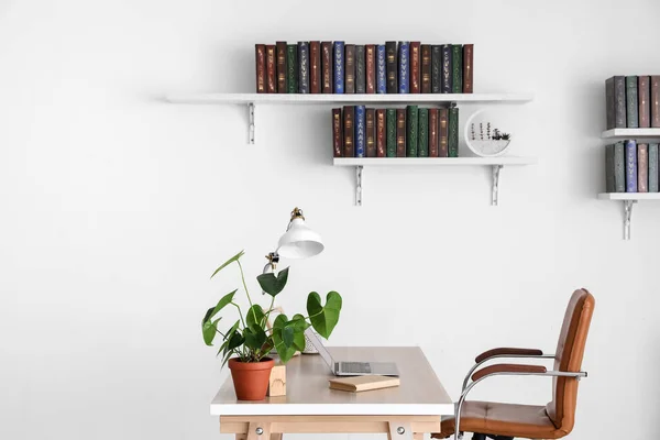 Table and books on shelves hanging on wall in interior of room