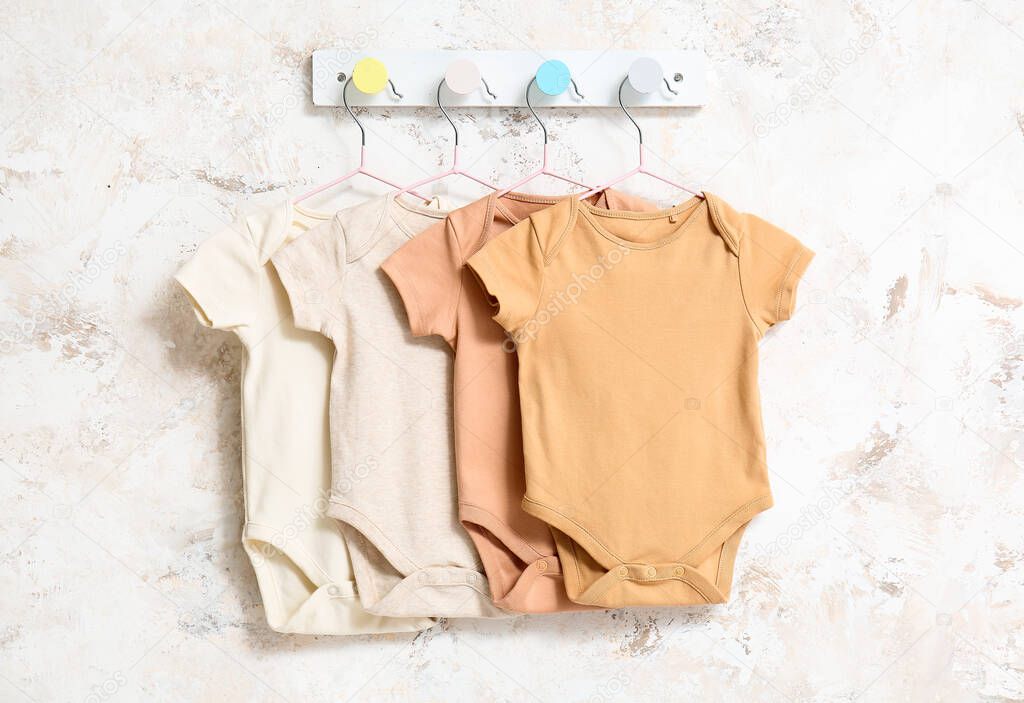 Baby bodysuits hanging on light wall