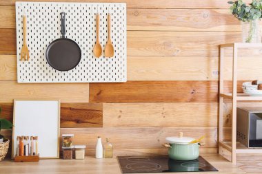 Tahta duvarda tava ve spatula asılı.