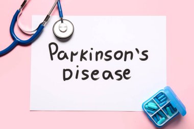 Parkinson Hastalığı, steteskop ve pembe arka planda haplar içeren kağıt kağıtlar.