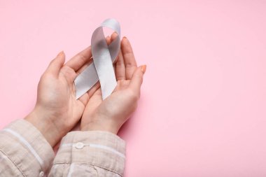 Pembe arka planda Parkinson 'un farkındalığı olan kadın.
