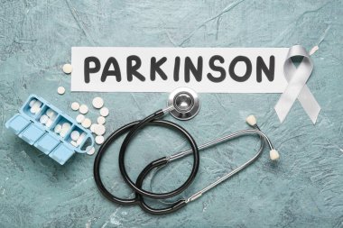 Kelime parkINSON, farkındalık kurdelesi, steteskop ve grunge arkaplanda haplar