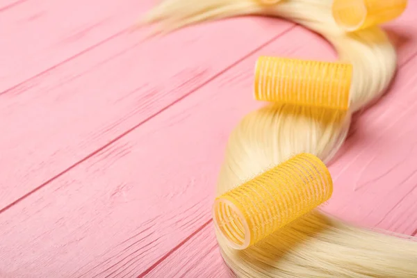 Gelbe Lockenwickler Mit Blonder Haarsträhne Auf Rosa Holzgrund Nahaufnahme — Stockfoto