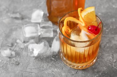 Gri arka planda bir bardak lezzetli eski moda kokteyl.