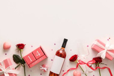 Sevgililer Günü tarihli takvim, şarap şişesi, kırmızı güller ve beyaz arka planda hediye kutuları