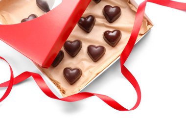 Beyaz arka planda kalp şeklinde şekerlerle dolu bir kutu.