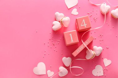 Sevgililer Günü tarihli takvim ve pembe arka planda kalp şeklinde lezzetli kurabiyeler.