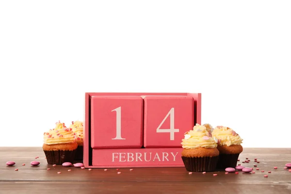 カレンダーバレンタインデーと白い背景を背景にテーブルの上のおいしいカップケーキ — ストック写真