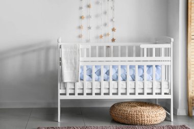 Beyaz beşik ve rattan puf Işık duvarının yanında