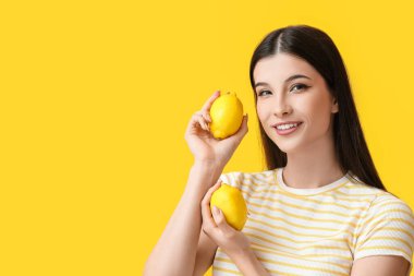 Renkli arka planda limonları olan güzel genç bir kadın.