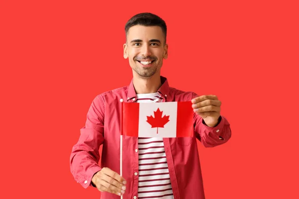 Kırmızı Arka Planda Kanada Bayrağı Taşıyan Mutlu Genç Adam — Stok fotoğraf
