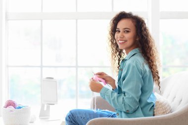 Genç Afro-Amerikalı kadın evde online örgü dersleri alıyor.