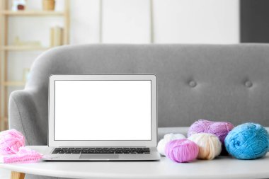 Dizüstü bilgisayar ve örgü iplikleri masanın üzerinde.