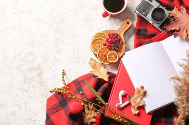 Boş kitap, bir fincan kahve, kulaklık ve arka planda süveter.