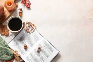 Kitaplar, bir fincan kahve, aksesuarlar ve arka planda sonbahar dekoru.