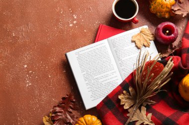 Kitap, bir fincan kahve ve arka planda sonbahar dekoru.