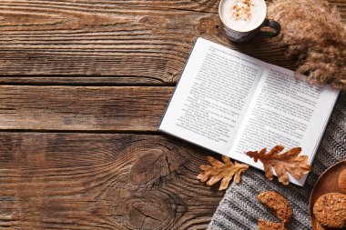 Kitap, kahve, kurabiye ve ahşap arka planda sonbahar dekoru.