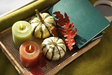 Kitaplı tepsi, balkabağı ve odada ekoseli mumlar