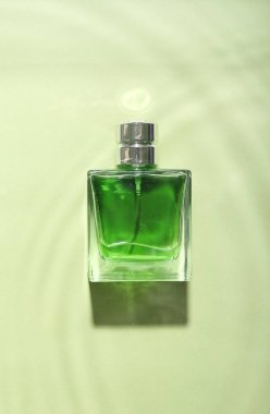 Yeşil arka planda bir şişe parfüm.