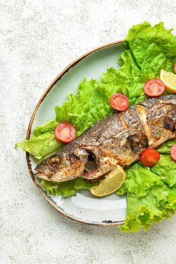 Açık arkaplanda lezzetli levrek ve sebze tabağı, yakın plan.