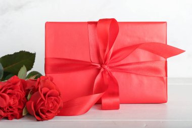 Sevgililer Günü hediyesi ve açık ahşap arka planda güller.