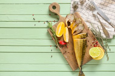 Yeşil ahşap arka planda kesilmiş füme uskumru balıklı tahta.