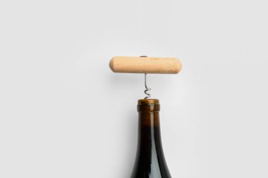 Beyaz arka planda bir şişe şarap ve tirbuşon, yakın plan.