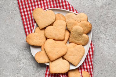 Gri arka planda lezzetli kalp şeklinde kurabiyeler olan tabak. Sevgililer Günü kutlaması