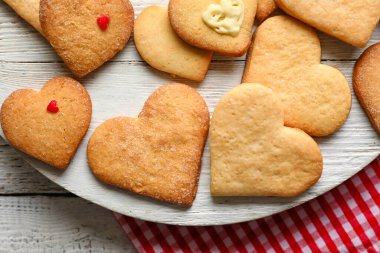 Beyaz ahşap arka planda, nefis kalp şekilli kurabiyeler olan tahta, yakın plan. Sevgililer Günü kutlaması