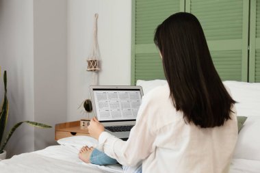 Yatak odasında dizüstü bilgisayarda takvim kullanan kadın