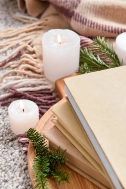 Kitap yığını, yanan mumlar ve ekoseli köknar dalları, yakın plan.