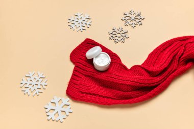 Örülmüş eşarp, kremalı kavanoz ve renkli kar taneleri.