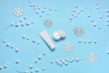 Mavi arka planda kozmetik ürünler ve kış dekoru