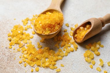 Tahta kaşık ve kepçeyle turuncu deniz tuzu hafif arka planda, yakın plan.