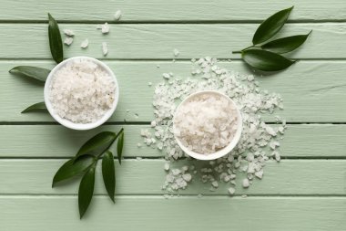 Kase dolusu deniz tuzu ve ağaç yapraklarıyla renklendirilmiş ahşap arka plan.