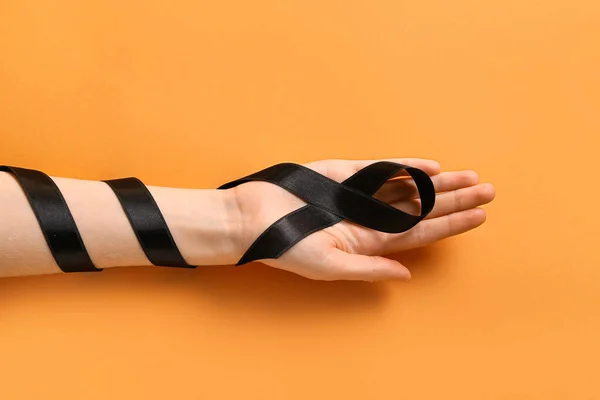 Γυναικείο Χέρι Μαύρη Κορδέλα Πορτοκαλί Φόντο Έννοια Μελανώματος — Φωτογραφία Αρχείου