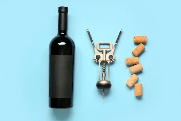 Bottle of wine, corks and opener on blue background